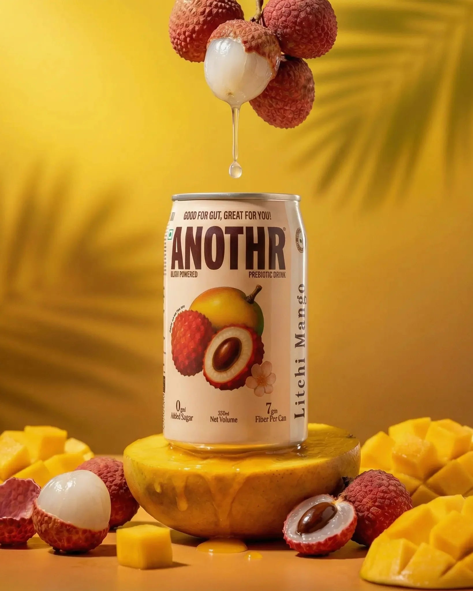 Can of 'Anothr' Litchi Mango drink with lychees and mangoes on a yellow background